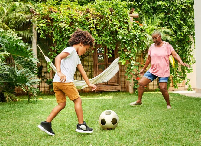 woman and child playing soccer in yard